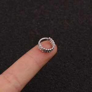 Detailed view of silver twisted triple-row hoop earrings held on fingers with black background