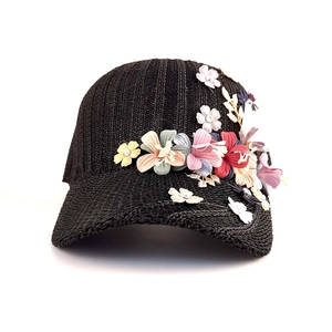 Detail of hand-crafted colorful fabric flowers on a black woven straw baseball cap