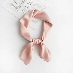 Close-up of a pink satin silk scarf tied neatly on a magazine with soft natural light