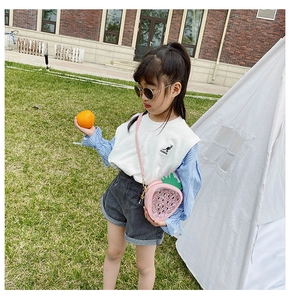 Pink sequin strawberry-shaped crossbody bag worn by a girl in an outdoor park