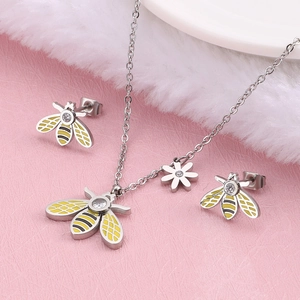 Silver bee jewelry set with yellow enamel wings and white zircon stones on pink background