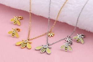 Macro shot of bee pendant necklace and stud earrings set with enamel and diamond accents