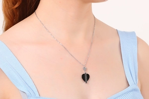 Vue détaillée d'un collier pendentif cœur en argent porté par un mannequin en studio