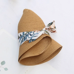 Detailed close-up of woven straw hat featuring a blue floral ribbon bow and foldable brim