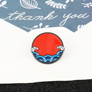 Detailed close-up of a round enamel brooch featuring a red sun and wave design on blue card