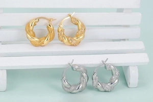 Vintage chunky twisted hoop earrings in gold and silver finish on a mini chair