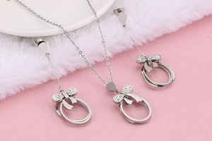 Close-up of silver bow jewelry set with sparkling zircons on soft pink background