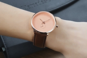 Detail of YOLAKO quartz watch with brown leather strap and peach dial on wrist