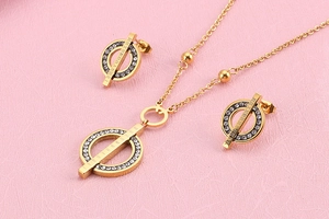 Detail view of Roman numeral clock design gold jewelry set with rhinestones on pink background