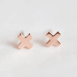 Macro shot of rose gold cross earrings showing polished finish and X-shaped design