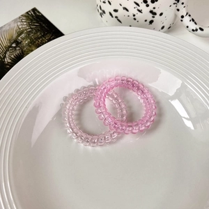Detailed view of two gradient pink spiral hair ties on a white plate with aesthetic decor