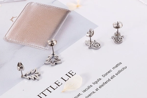 Detailed flat lay of silver Hamsa hand and Christmas tree stainless steel stud earrings