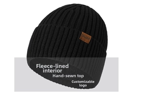 Close-up of a black chunky knit beanie featuring a cozy fleece lining and leather logo tag