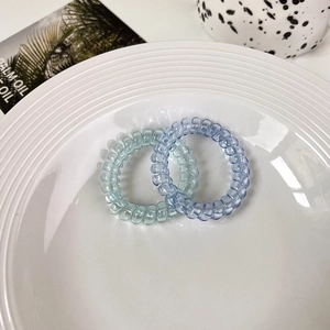 Detail of light blue and light cyan gradient spiral hair ties on a white ceramic plate