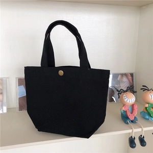 Detail of black canvas lunch tote bag featuring a metallic snap button closure and sturdy handle