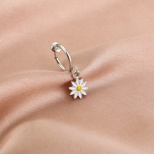 Close-up of silver daisy pendant earring on champagne silk background with soft lighting