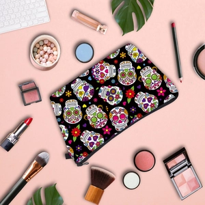 Flat lay of skull print makeup bag with lipsticks and brushes on a pink background