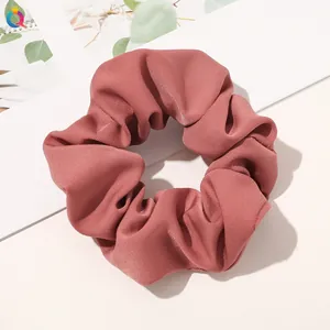 Detail of dusty rose plaid fabric scrunchie with soft pleated texture and elastic band