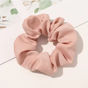 Detail view of pink plaid fabric scrunchie with soft pleated texture and elastic core