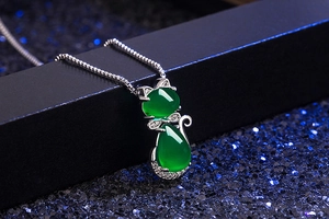 Macro detail of cat pendant necklace with green agate and cubic zirconia on jewelry box