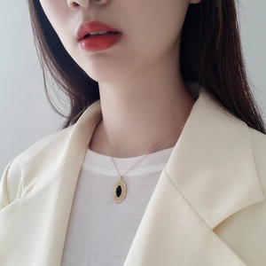 Close-up of gold oval sunburst pendant with black onyx stone worn on a model