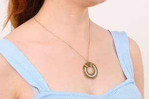 Detail of a gold-plated titanium necklace with a circular hollow diamond-set pendant