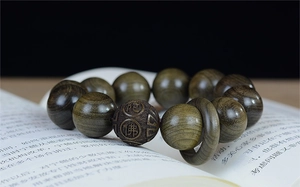 Vue macro d'un chapelet en bois de santal avec sculpture de Bouddha sur un livre ouvert