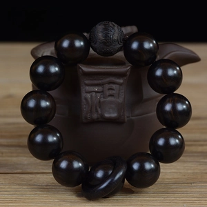 Gros plan d'un bracelet bouddhiste en bois noir de 20mm avec mantra gravé à la main