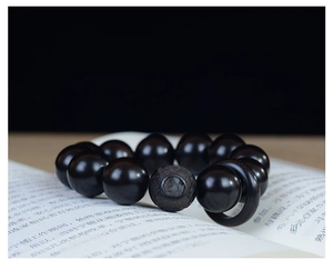 Vue macro de perles en bois de santal foncé 20mm avec perle centrale gravée sur un livre