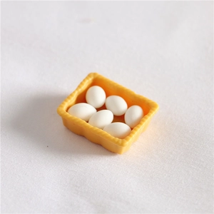Detailed close-up of a miniature yellow egg tray with six tiny white eggs for dollhouse