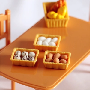 Miniature dollhouse food accessories with colorful eggs and bread in yellow baskets on a table