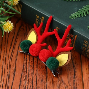 Détail d'une pince à cheveux renne de Noël avec pompons rouges et verts et petites oreilles
