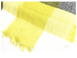 Detailed macro view of yellow and grey plaid cashmere-like scarf with soft fringe edges