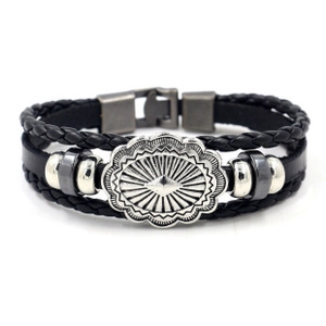 Dettaglio del bracciale aquila multistrato con cordino in pelle nera e medaglia sole argento