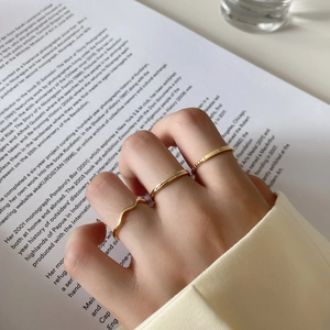 Three-piece gold plated minimalist stackable ring set shown on fingers over book pages