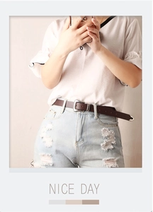 Brown vintage leather belt with silver engraved buckle on light blue ripped jeans