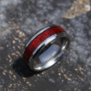Macro shot of 8mm silver steel ring with red wood inlay on a textured stone surface