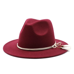 Detail of burgundy wide brim fedora with white tassel cord and gold buckle accent