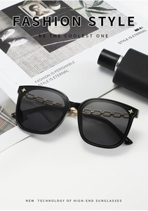 Détail de lunettes de soleil carrées noires avec chaîne dorée et étoiles sur la monture
