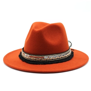 Detail view of orange fedora with ethnic ribbon, sequins, and black fringe trim