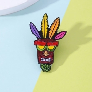Detail of colorful Aku Aku mask enamel pin with black plating on yellow and blue background