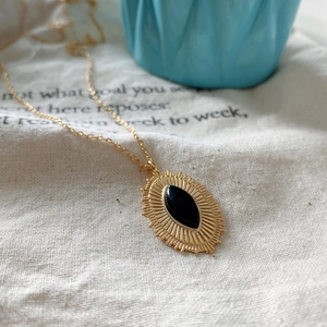 Macro detail of sunburst pendant with black marquise agate on gold-plated silver chain