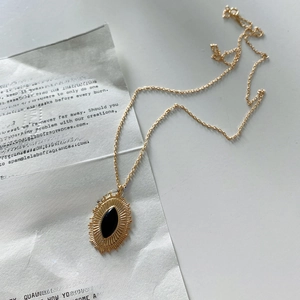 Macro detail of 925 silver necklace featuring black onyx pendant on vintage text background