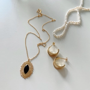 Close-up of gold-plated necklace with black agate pendant and matching C-shape earrings