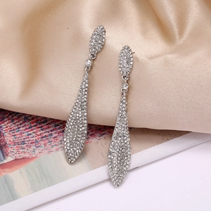 Detailed close-up of luxury teardrop earrings with crystals on beige silk fabric
