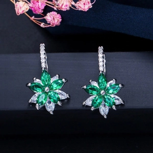 Détail des boucles d'oreilles fleurs avec pierres émeraude et blanches sur monture argent