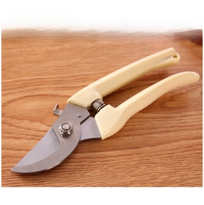 Detail view of ergonomic garden pruning shears with curved steel blades on wood background