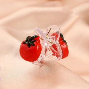 Close-up of cute red tomato acetate hair claw clip for kids on satin background