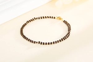Détail d'un bracelet bohème à double couche avec perles sombres et chaîne dorée