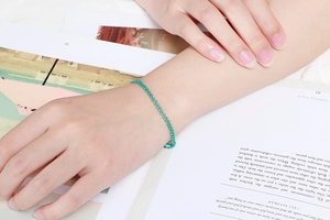 Détail du bracelet minimaliste en perles vertes porté au poignet pour un style boho